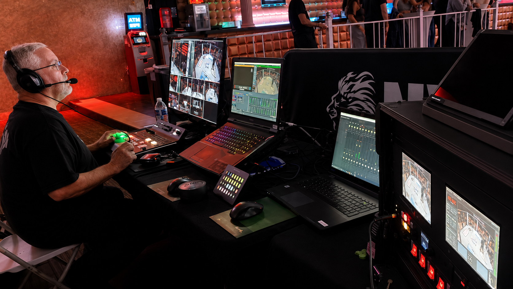 The on-site production control area managed live switching, streaming, graphics, replay, audio, recording, and technical monitoring. Live video production control station with multiview displays, streaming computers, switcher, and operator.
