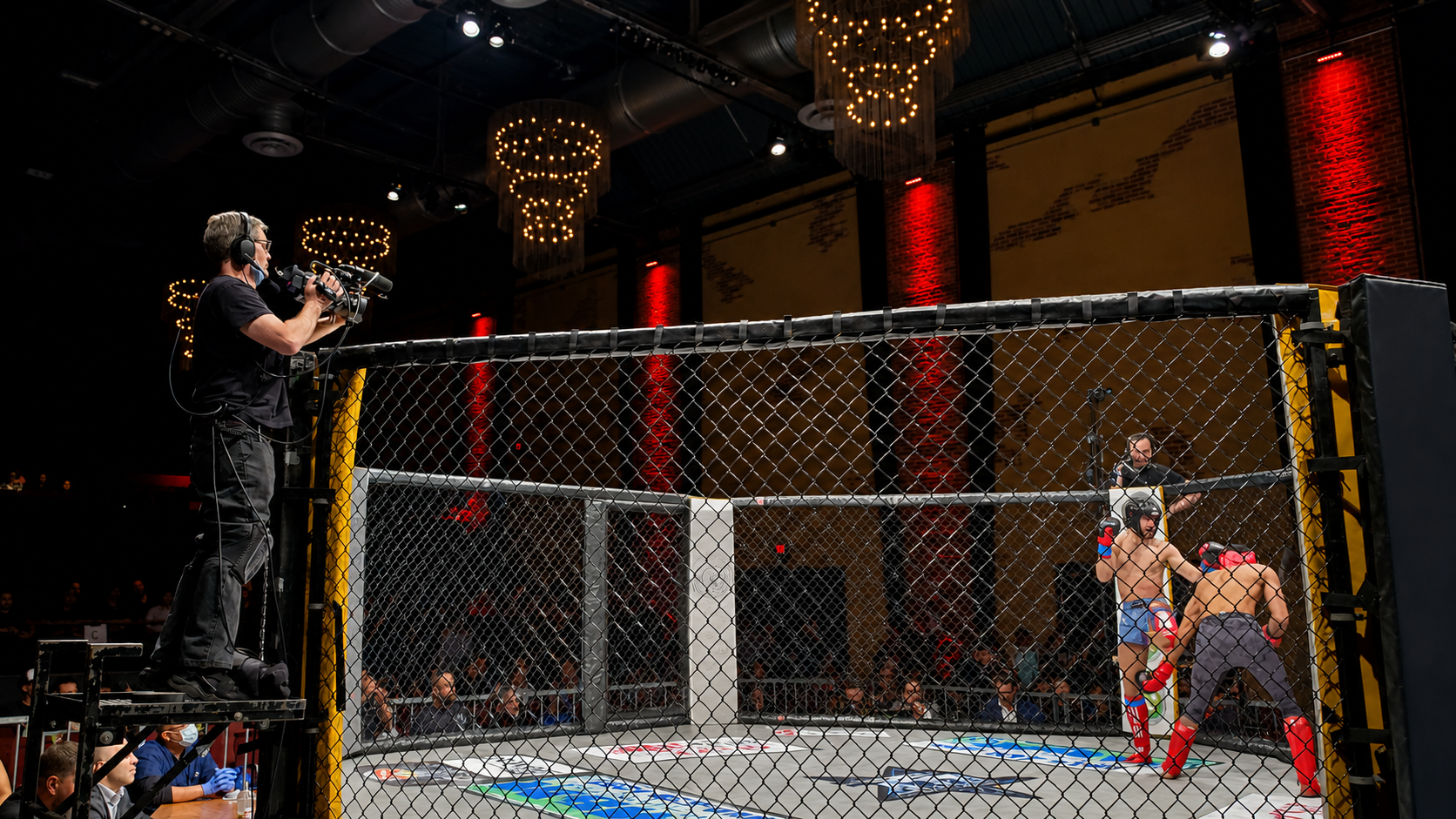 Strategic camera positions provided clear coverage of the fighters, officials, cage action, and audience reactions. Digital Art Video camera operator filming an Extreme Cage Fighting match from an elevated platform.